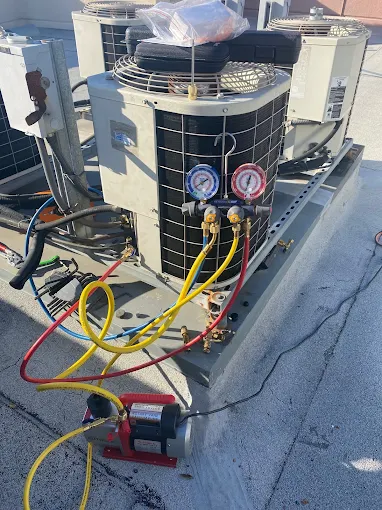 Technician charging refrigerant on rooftop AC unit